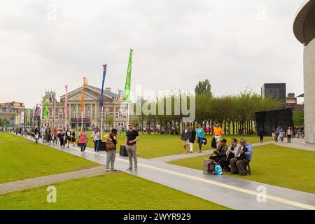 Museumsplatz mit Blick auf die Konzerthalle voller Wandertouristen und drei Musiker im Vordergrund in Amsterdam. Stockfoto