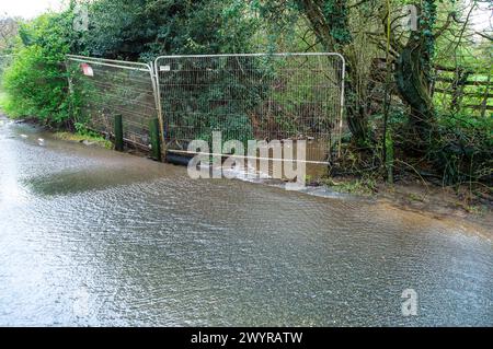 Harefield, Großbritannien. April 2024. Das Wasser fließt über eine Landstraße in Harefield in der Nähe der Stelle, an der HS2 das High Speed Rail Viaduct für die High Speed Rail von London nach Birmingham bauen wird. HS2 hat Felder ausgegraben, zahlreiche Bäume gefällt und Hecken zerstört. Die Wasserstraßen, an denen HS2 arbeitet, müssen neue Routen finden, von denen die Einheimischen glauben, dass sie die Überschwemmungen in West London und den Chilterns verschärfen. Quelle: Maureen McLean/Alamy Live News Stockfoto