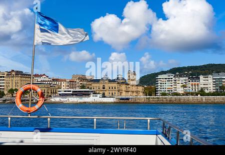 Barco turístico navegando por la Bahia de La Concha, forma parte de la excursión que se realiza desde el Puerto Donostiarra a la Isla Santa Clara, donde se encuentra la Casa del Faro con la obra Hondalea de la escultora Cristina Iglesias, Al fondo el Parque Alderdi Eder, el edificio del Club Nautico y el Ayuntamiento, Bahia de La Concha, Donostia, San Sebastian, Baskenland, Spanien, Europa. Stockfoto