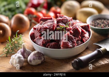 Stücke geschnittenes Rindfleisch in einer Schüssel mit Gemüse, bereit für Gulasch. Stockfoto