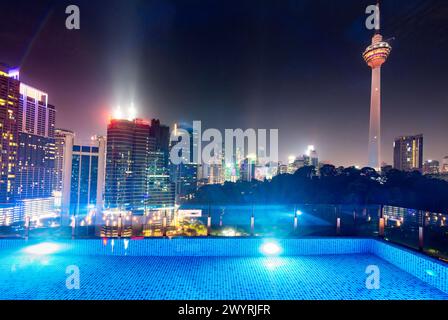 Atemberaubender Blick auf die Wolkenkratzer der Stadt KL, nachts hell beleuchtet, eleganter Pool im Vordergrund mit atemberaubendem Panoramablick Stockfoto