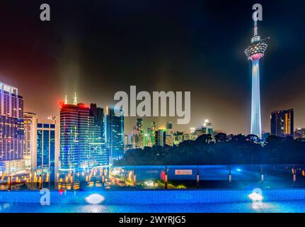 Atemberaubender Blick auf die Wolkenkratzer der Stadt KL, nachts hell beleuchtet, eleganter Pool im Vordergrund mit atemberaubendem Panoramablick Stockfoto