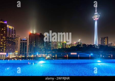 Atemberaubender Blick auf die Wolkenkratzer der Stadt KL, nachts hell beleuchtet, eleganter Pool im Vordergrund mit atemberaubendem Panoramablick Stockfoto