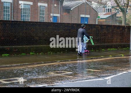 Chesham, Buckinghamshire, Großbritannien. April 2024. Wasser strömt aus einem verstopften Abfluss auf einer Hauptstraße durch Chesham, Buckinghamhire. Einige Autos fuhren schnell durch das Wasser und spritzten Passanten vorbei. Kredit: Maureen McLean/Alamy Stockfoto