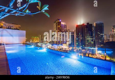 Atemberaubender Blick auf die Wolkenkratzer der Stadt KL, nachts hell beleuchtet, eleganter Pool im Vordergrund mit atemberaubendem Panoramablick Stockfoto