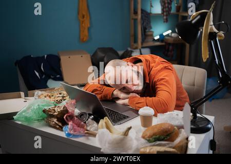 Chaos, Störung und Menschenkonzept. Müde Freelancer schläft in einem unordentlichen Wohnzimmer mit verstreuten Sachen Stockfoto