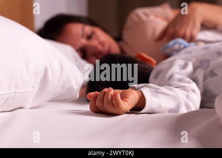 Müde Mutter mit Baby, das im Bett schläft Stockfoto