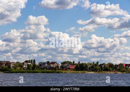 Häuser am Ufer des Flusses bei bewölktem Wetter, ländliche Landschaft Stockfoto