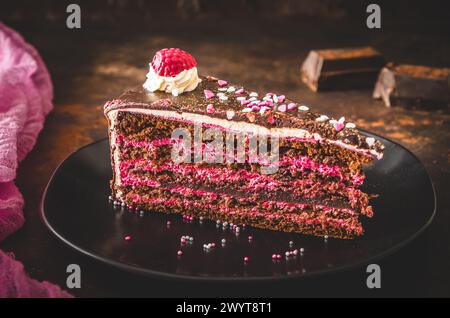 Ein Stück Himbeer-Schokoladen-Torte auf einem schwarzen Teller Dunkelbrauner Hintergrund Stockfoto