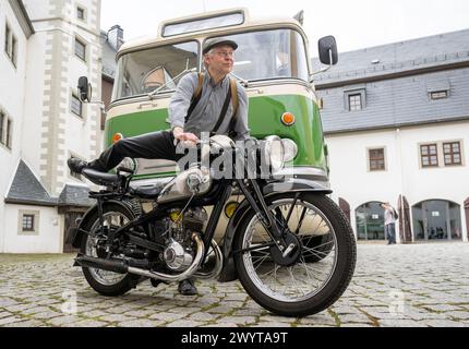 Zschopau, Deutschland. April 2024. Dirk Schmerschneider vom Museum für sächsische Fahrzeuge Chemnitz bestieg seinen 1937 DKW SB 200 vor einem historischen Ikarus 55,51 Bus von 1962 im Innenhof von Schloss Wildeck. An vier Tagen in den kommenden Monaten können Interessenten die vier sächsischen Motorradmuseen im Oldtimerbus besuchen. Quelle: Hendrik Schmidt/dpa/Alamy Live News Stockfoto