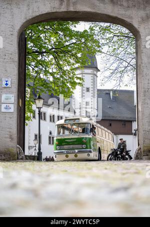 Zschopau, Deutschland. April 2024. Busfahrer Sven Mischke (l) und Dirk Schmerschneider vom Museum für Sächsische Fahrzeuge Chemnitz auf einem DKW SB 200 sprechen über einen historischen Ikarus-Bus 55,51 von 1962 im Innenhof von Schloss Wildeck. An vier Tagen in den kommenden Monaten können Interessenten die vier sächsischen Motorradmuseen im Oldtimerbus besuchen. Quelle: Hendrik Schmidt/dpa/Alamy Live News Stockfoto