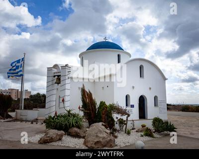 Paphos, Zypern - 23. Dezember 2023: Kleine bezaubernde, weiß-blaue St. Nikolaus-Kirche an der Küste. Stockfoto