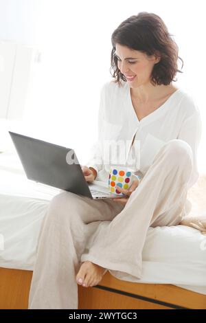Frau, die einen Laptop benutzt und lächelt. Stockfoto