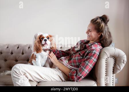 Schöne Frau sitzt mit Spaniel Hund in einer hellen Wohnung in hellem Interieur, entspannen Sie auf dem Sofa. Stockfoto