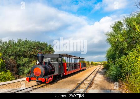 Der Retro-Zug bringt Besucher vom Festland zum Strand Barril in der Nähe von Tavira, Portugal. Stockfoto