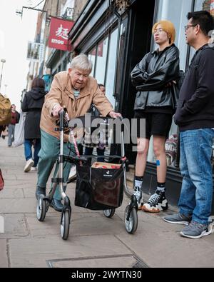 Eine ältere Dame in der Stadt, die auf der Hauptstraße ist Stockfoto