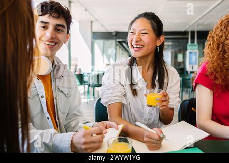 Glückliche junge, vielfältige Gruppe von Studenten, die zusammen am Campus College sitzen. Stockfoto