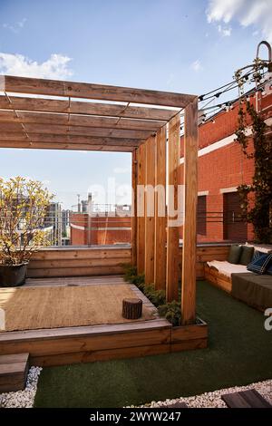 Ein gemütlicher Wohnbereich im Freien mit einer schönen Holzpergola umgeben von üppigem Grün, einladenden Sitzgelegenheiten und einer ruhigen Atmosphäre Stockfoto