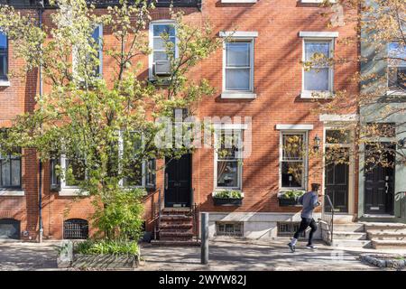 Läufer auf dem Gehweg vor Reihenhäusern, Fitlers Square Nachbarschaft, Philadelphia, Pennsylvania, USA Stockfoto