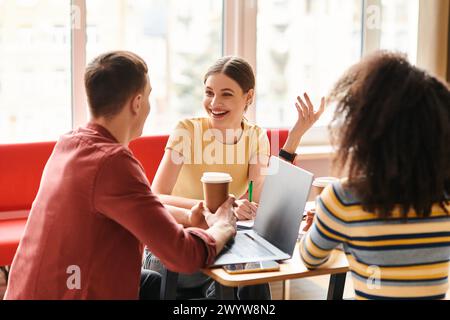 Eine multikulturelle Gruppe von Schülern arbeitet an einem Tisch zusammen, die sich alle auf ihre Laptops konzentrieren, und führt eine produktive Diskussion. Stockfoto