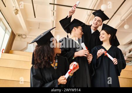 Eine Gruppe von Absolventen in bunten Gewändern und Mützen stehen zusammen, voller Freude und Feier an ihrem Abschlussfeiertag. Stockfoto