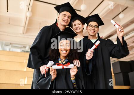 Verschiedene Gruppen von Studenten in Abschlusskleidern und akademischen Mützen lächeln glücklich für ein Foto drinnen. Stockfoto