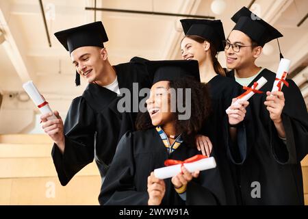 Multikulturelle Gruppe glücklicher Absolventen in Gewändern mit Diplomen. Stockfoto