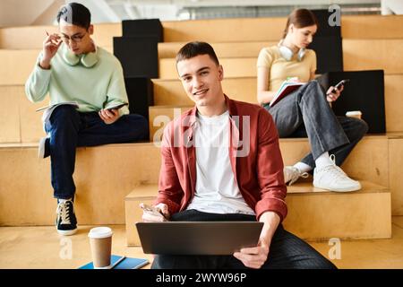 Ein Mann, der draußen auf Stufen sitzt und sich auf seinen Laptop konzentriert hat Stockfoto