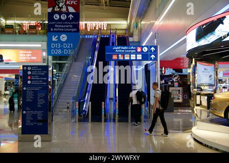 DUBAI, VEREINIGTE ARABISCHE EMIRATES - 21. JUN 2019: Rolltreppen und Schilder zu Flughafen-Lounges im Abflugbereich des Dubai Airport DXB Stockfoto