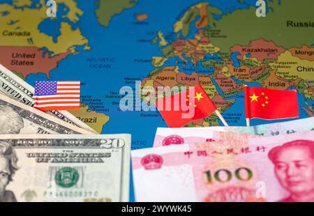 Ein geopolitisches Wirtschaftskonzept mit US-Dollar, amerikanischer Flagge, chinesischem Yuan und Flaggen auf einer Weltkarte. Stockfoto