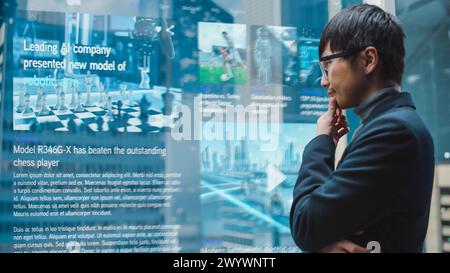 Eleganter japanischer Geschäftsmann, der mit dem futuristischen, fortschrittlichen holografischen Bildschirm im Aufzug durch die Nachrichten scannt. Succesful Male fährt zum Büro im modernen Buisness Center. Stockfoto
