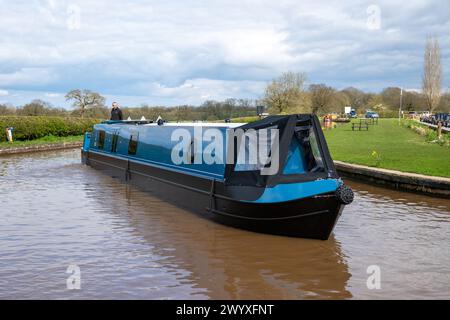 Brandneues blaues Schmalboot, gebaut von Knights Schmalbooten aus Cheshire, das an einem hellen Frühlingstag aus einem Yachthafen auf den Shropshire Union Canal gefahren wird. Stockfoto