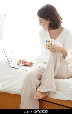 Frau, die einen Laptop benutzt und lächelt. Stockfoto