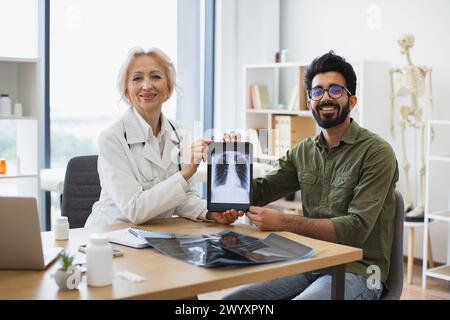 Senior Professional und Happy Lady posieren mit CT-Scan-Bild auf Tablet. Stockfoto