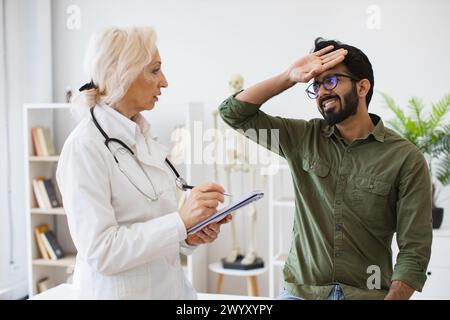 Ältester Arzt, der Empfehlungen gibt und Rezepte schreibt. Stockfoto