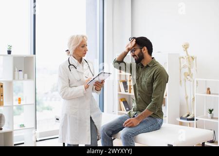 Ältester Arzt, der Empfehlungen gibt und Rezepte schreibt. Stockfoto