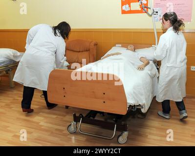 Pflegestudenten betreuen einen Puppenpuppen-Patienten, der in einem Krankenhausbett in Zamora liegt. Stockfoto