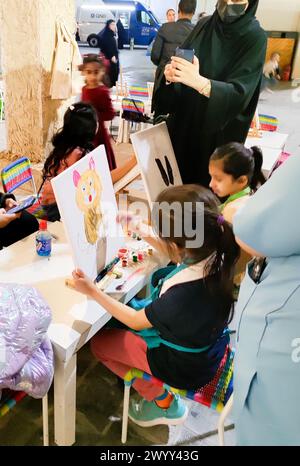 Ein kleines Mädchen färbt ein Gemälde bei der Feier zum Nationalfeiertag in Katar. Stockfoto