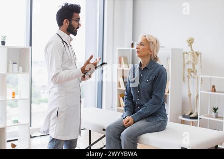Erwachsener bärtiger Arzt, der Empfehlungen gibt und Tablette verwendet. Stockfoto