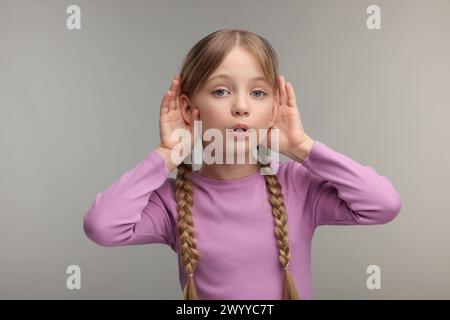 Kleines Mädchen mit Hörproblemen auf grauem Hintergrund Stockfoto