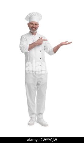 Glücklicher Koch in Uniform, der auf etwas auf weißem Hintergrund zeigt Stockfoto
