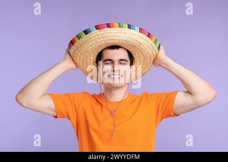 Junger Mann mit mexikanischem Sombrero-Hut auf violettem Hintergrund Stockfoto