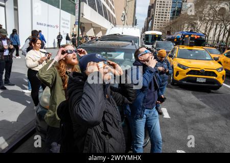 Im Bryant Park in Midtown, Manhattan, versammeln sich Menschenmassen, um die teilweise Sonnenfinsternis am 8. April 2024 zu beobachten. Stockfoto