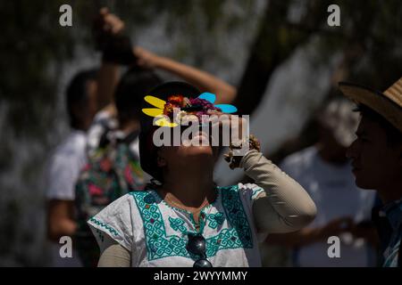 Mexiko Stadt, Mexiko. April 2024. Eine Frau benutzt eine Schutzbrille, um die Sonnenfinsternis vom Pirámide Cerro de la Estrella aus zu sehen. Millionen Menschen in Mexiko, den USA und Kanada erlebten am Montag eine totale Sonnenfinsternis. Ein solches himmlisches Spektakel tritt auf, wenn der Mond zwischen Sonne und Erde vorbeizieht und die Sonne vollständig bedeckt. Quelle: Jair Cabrera Torres/dpa/Alamy Live News Stockfoto