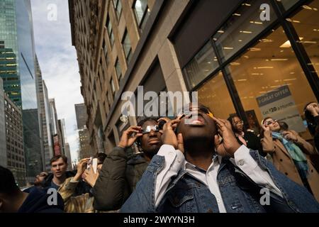 New York, New York, USA 8. April 2024 Menschen in Midtown Manhattan beobachten, wie der Mond während der Sonnenfinsternis vor der Sonne vorbeigeht, der etwa 90 % der Gesamtbevölkerung im Raum New York City produzierte Stockfoto