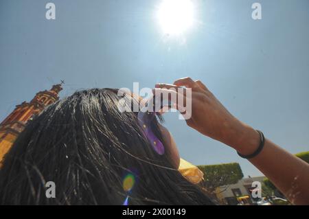 San Juan Del Rio, Mexiko. April 2024. Eine Frau beobachtet die Sonnenfinsternis durch eine spezielle Sichtbrille. Große Menschenmassen versammeln sich um den Hauptplatz von San Juan del Rio, um eine teilweise Sonnenfinsternis während der Großen Nordamerikanischen Sonnenfinsternis zu erleben. Am 8. April 2024 in Mazatlan, Mexiko. (Foto: Fernando Camacho/ Credit: Eyepix Group/Alamy Live News Stockfoto