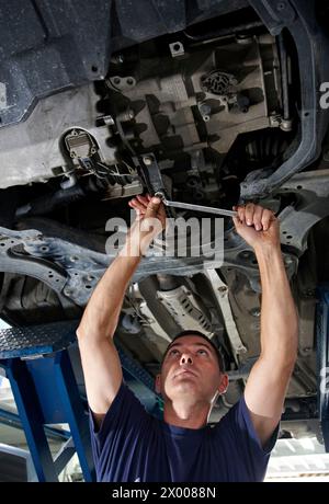 Arbeiter mit Ringschlüssel in der Autowerkstatt. Stockfoto