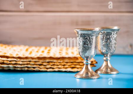 Alles Gute zum pessach. Metallkelch und traditionelle Matzah auf blauem Hintergrund. Symbole des jüdischen Feiertags. Stockfoto