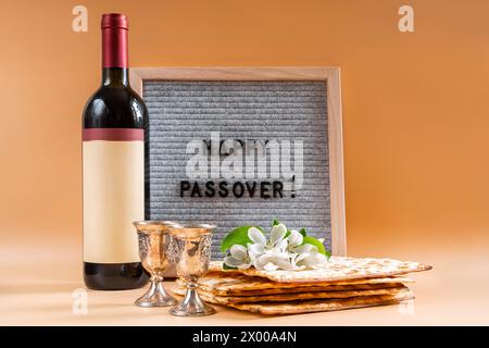 Jüdische Feiertage Pessach. Flasche Wein, Frühlingsblumen und Matzah-Brot auf beigefarbenem Hintergrund. Stockfoto