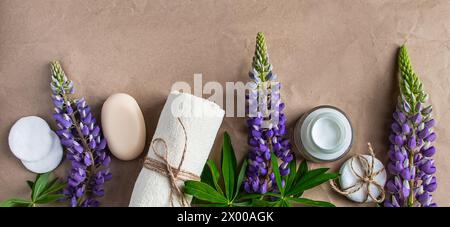 Natürliche Bio-Kosmetik und Lupine Blumen auf Bastelpapier Hintergrund. Feuchtigkeitsspendende Creme, Seife und Handtuch. Körperpflegekonzept. Spa und Schönheitsbehandlungen Stockfoto